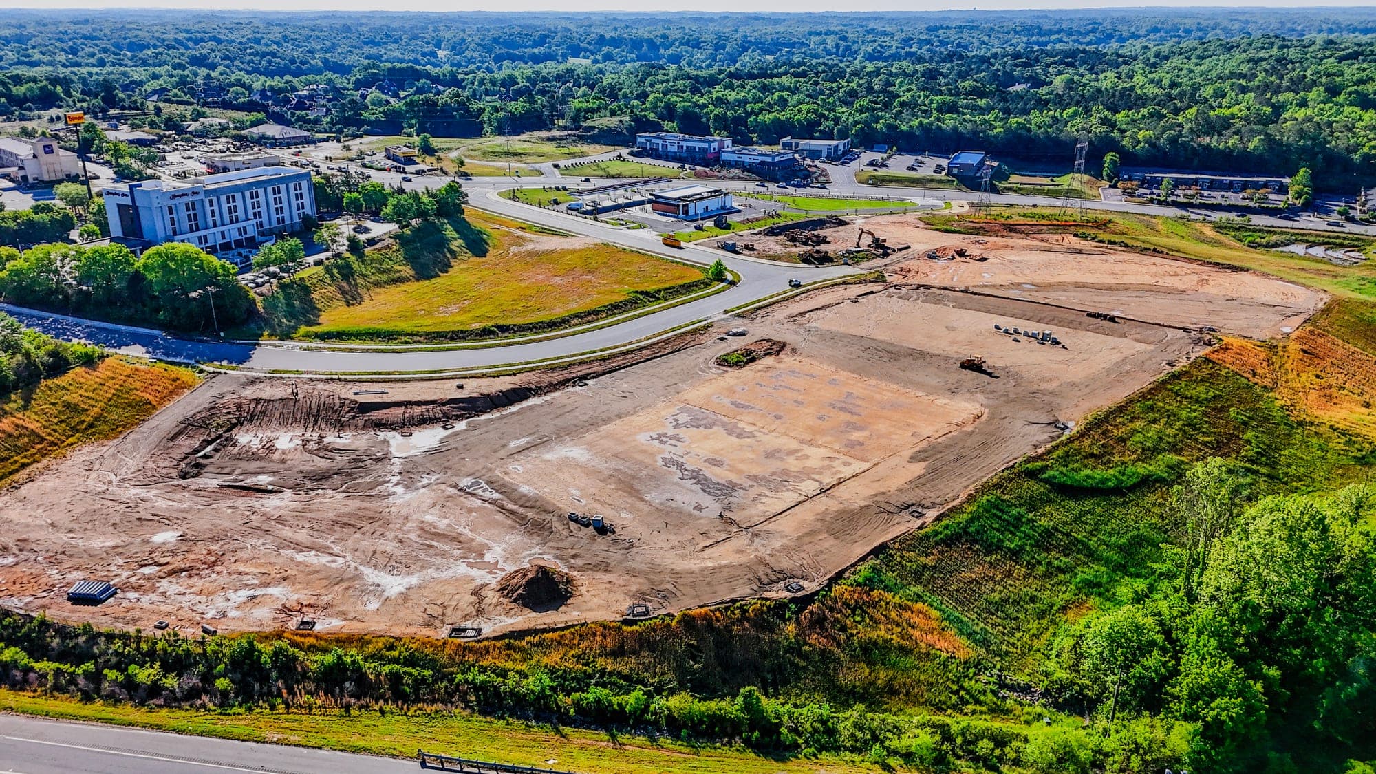 Aerial view of an active construction site with early structures and graded earth